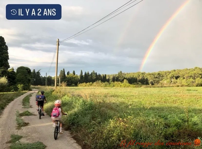 Des enfants en vélo, avec un arc-en-ciel